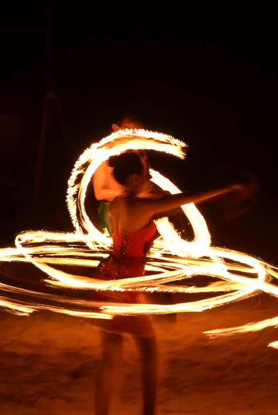 A performer is creating light patterns in the dark with fire.